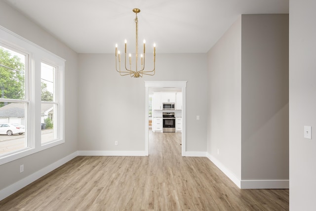 unfurnished dining area featuring baseboards, a chandelier, and light wood-style floors