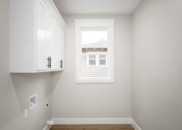 clothes washing area featuring washer hookup, electric dryer hookup, cabinet space, wood finished floors, and baseboards