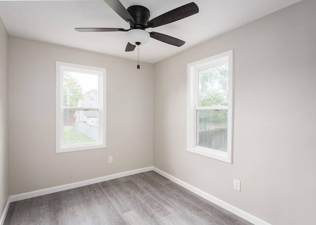 empty room with baseboards, plenty of natural light, a ceiling fan, and wood finished floors