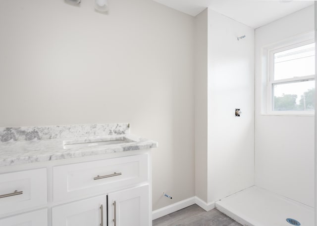 bathroom featuring vanity, baseboards, a stall shower, and wood finished floors