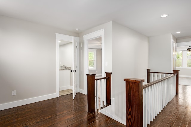 hall with baseboards, recessed lighting, wood finished floors, and an upstairs landing