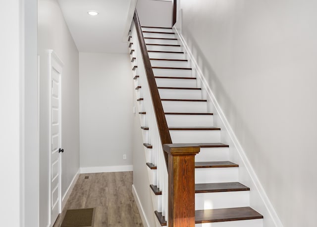 stairway featuring baseboards, recessed lighting, wood finished floors, and visible vents
