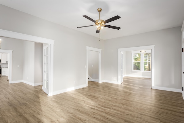 spare room with light wood-style floors, a ceiling fan, and baseboards