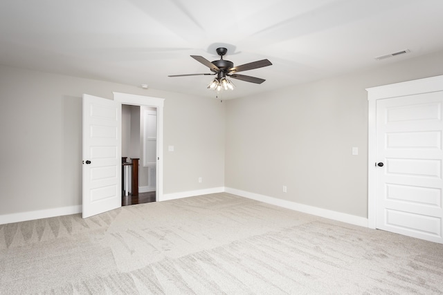 carpeted empty room with visible vents, baseboards, and ceiling fan