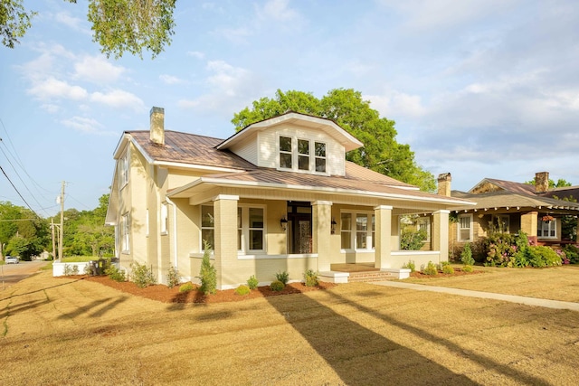 view of front of home featuring brick siding, a porch, a chimney, a standing seam roof, and metal roof