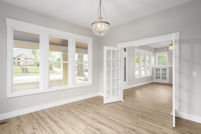 unfurnished dining area featuring light wood-type flooring, baseboards, and ceiling fan with notable chandelier