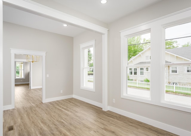 empty room featuring a healthy amount of sunlight, an inviting chandelier, and visible vents