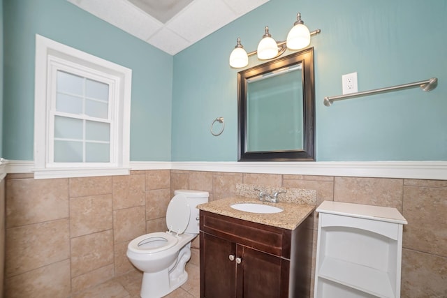  - bathroom featuring tile walls, toilet, wainscoting, vanity, and tile patterned floors