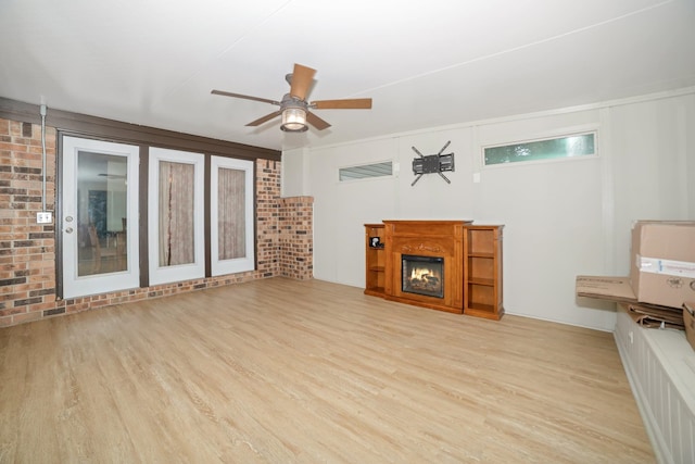  - unfurnished living room featuring wood finished floors, ceiling fan, and a warm lit fireplace