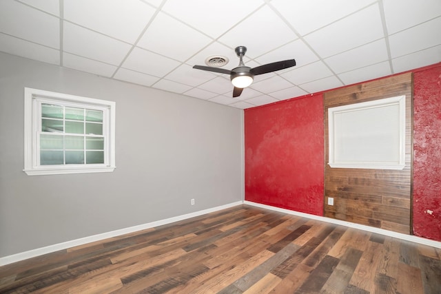  - unfurnished room featuring ceiling fan, wood finished floors, a drop ceiling, and baseboards