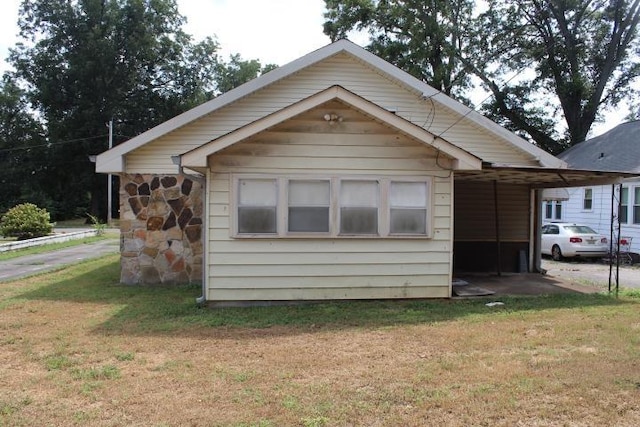 view of side of property featuring a carport and a lawn