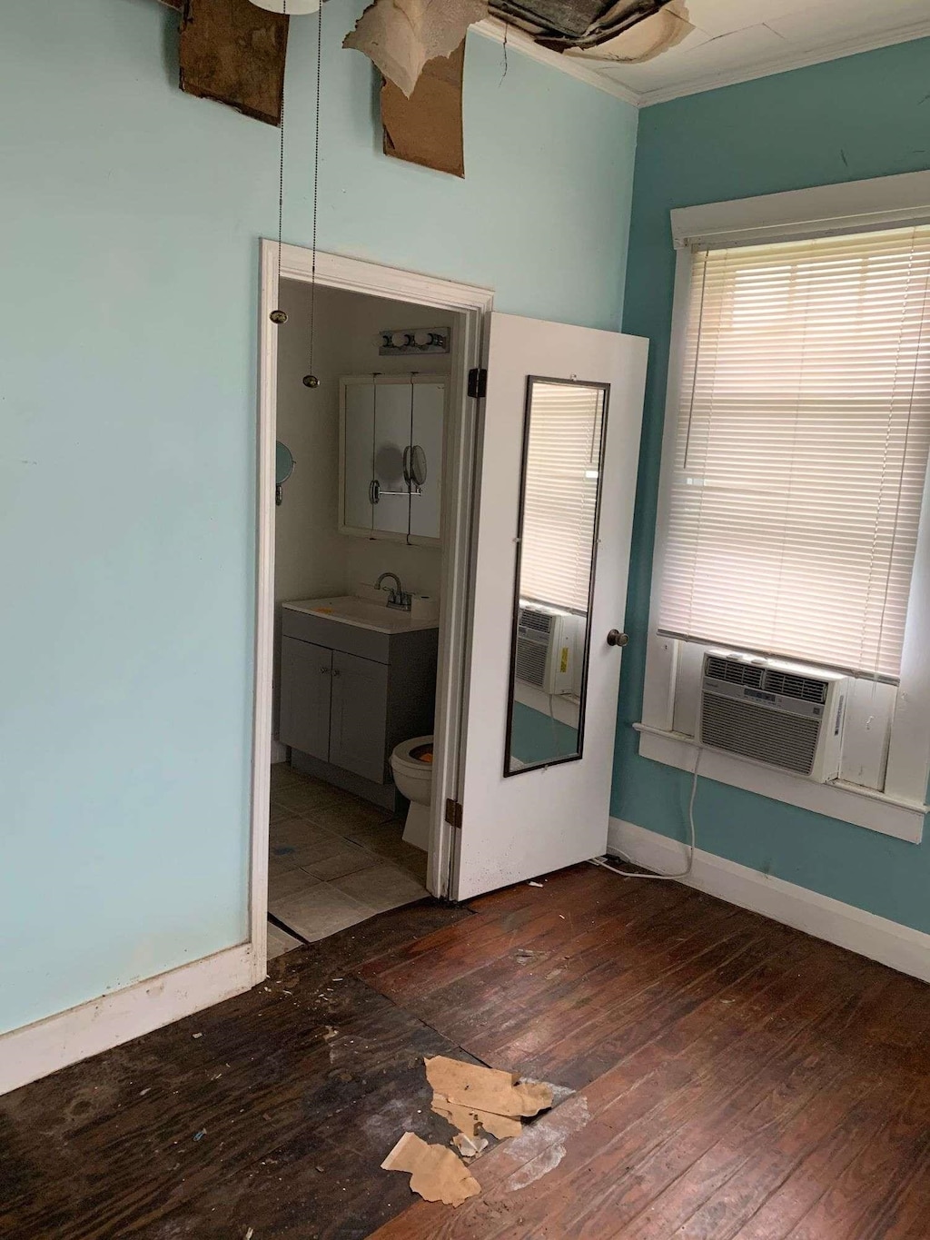unfurnished bedroom with a sink, hardwood / wood-style floors, cooling unit, and connected bathroom
