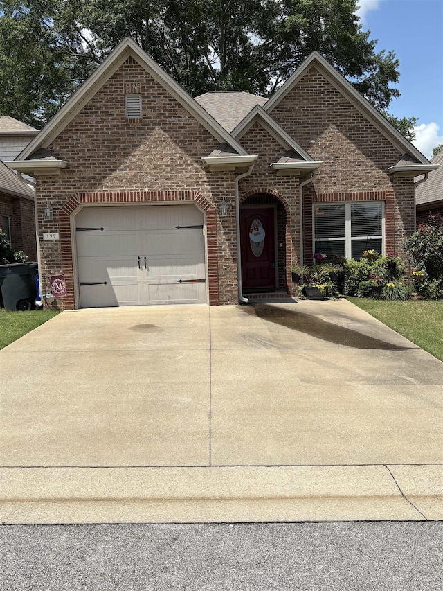 - view of front of house featuring brick siding, concrete driveway, and an attached garage
