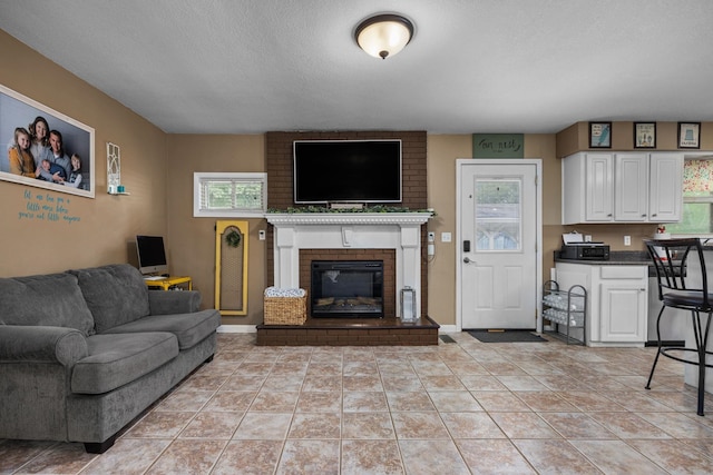 living room with a fireplace, light tile patterned flooring, and a textured ceiling