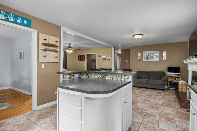 kitchen featuring a textured ceiling, ceiling fan, a center island, white cabinetry, and light tile patterned flooring