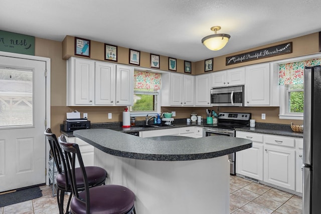 kitchen with a breakfast bar, white cabinetry, and stainless steel appliances