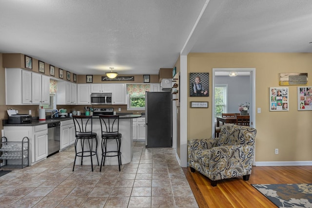 kitchen featuring white cabinets, a textured ceiling, a kitchen island, a kitchen bar, and stainless steel appliances