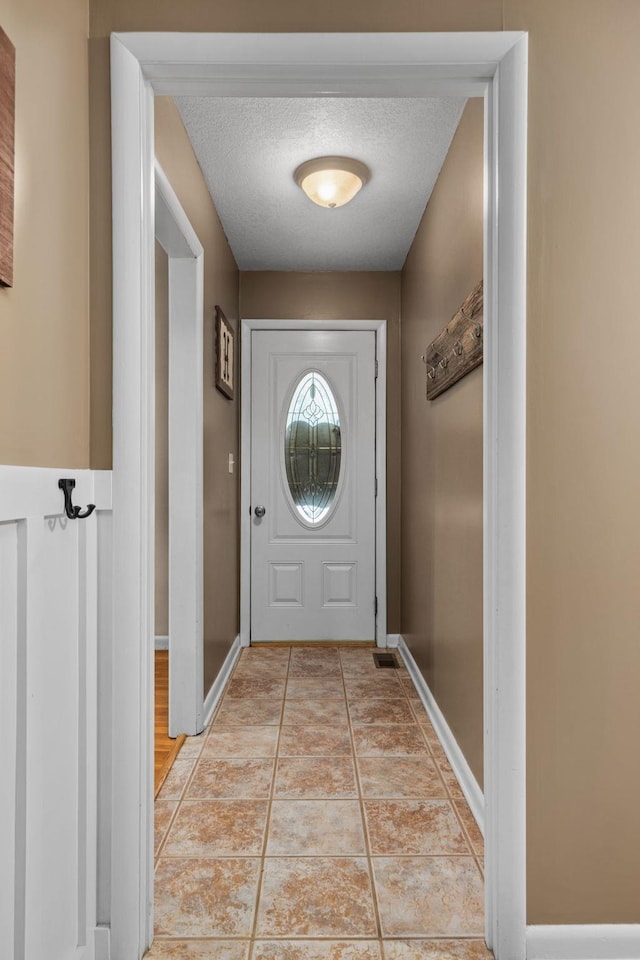 doorway to outside with light tile patterned floors and a textured ceiling