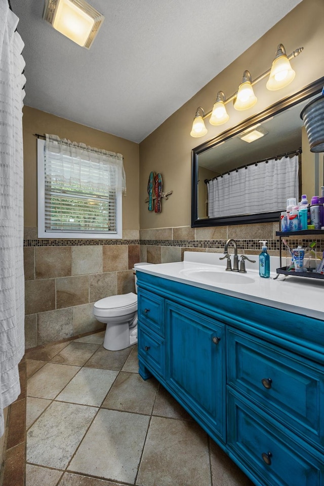 bathroom with vanity, toilet, and tile walls