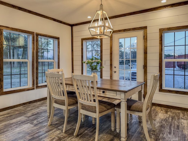 dining space featuring a notable chandelier, wooden walls, ornamental molding, and dark hardwood / wood-style floors