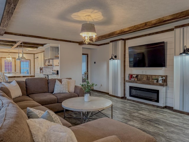 living room with a textured ceiling, wood-type flooring, ornamental molding, and beamed ceiling