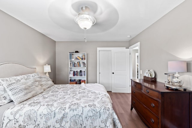 bedroom with ceiling fan, wood-type flooring, and a closet