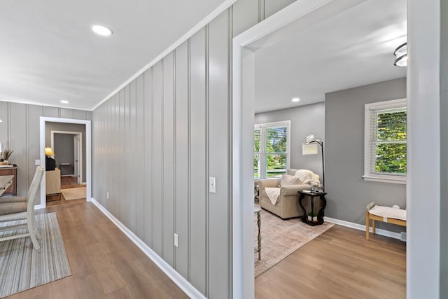 corridor featuring a healthy amount of sunlight, light wood-type flooring, and ornamental molding