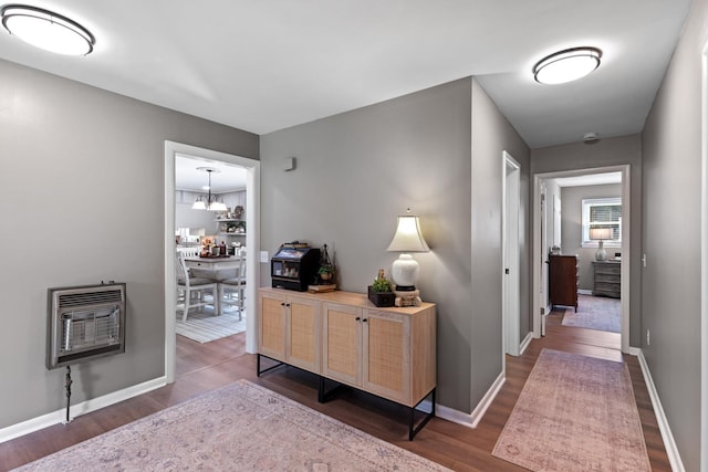 hallway with a notable chandelier, dark hardwood / wood-style flooring, and heating unit