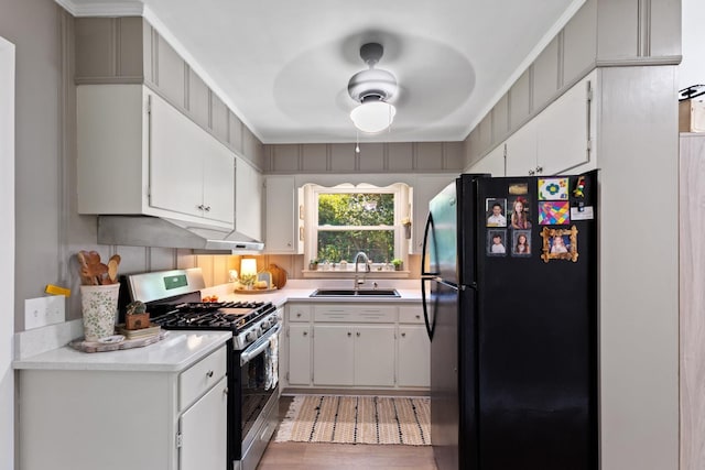 kitchen featuring white cabinetry, sink, black fridge, stainless steel range with gas stovetop, and ornamental molding