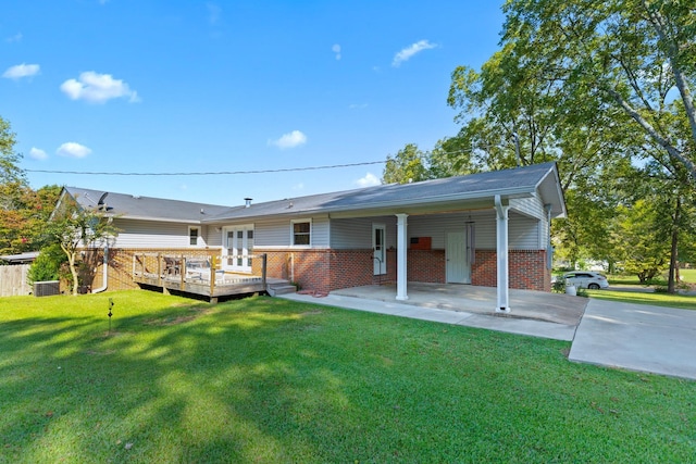 rear view of property with a lawn, a carport, and a deck