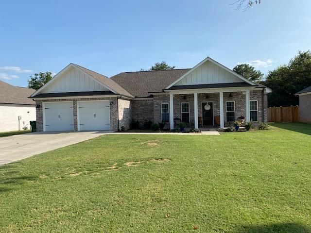 view of front of house featuring covered porch, a garage, and a front lawn