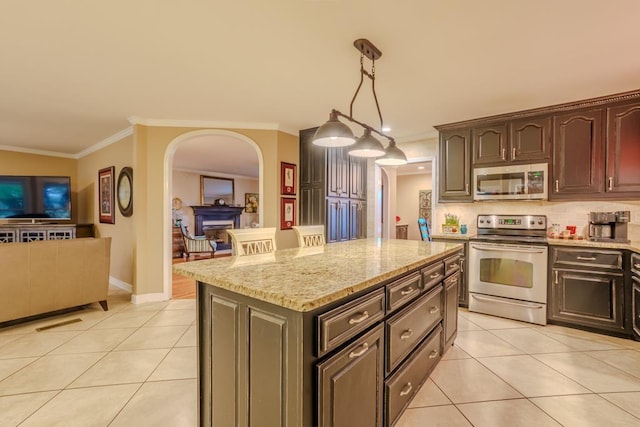 kitchen with dark brown cabinets, stainless steel appliances, pendant lighting, light tile patterned floors, and a kitchen island