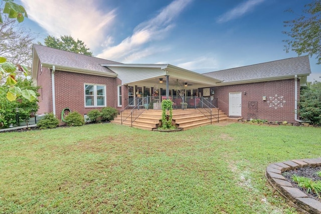 rear view of property featuring a lawn, ceiling fan, and a deck