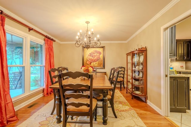 dining area featuring a notable chandelier, light hardwood / wood-style floors, and ornamental molding