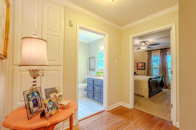 hall with ornamental molding and light wood-type flooring