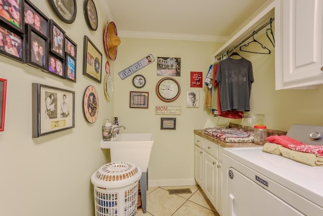 laundry area featuring cabinets, light tile patterned floors, and ornamental molding