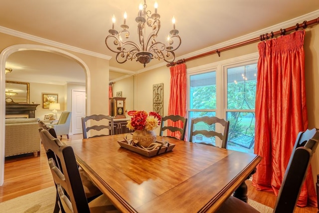 dining area with crown molding, a chandelier, and light wood-type flooring