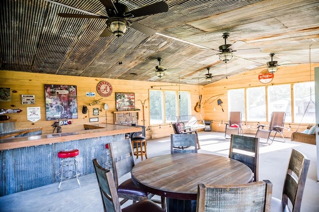 dining room featuring bar area, lofted ceiling, wooden ceiling, and wood walls