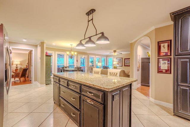 kitchen with stainless steel refrigerator with ice dispenser, a center island, decorative light fixtures, and ornamental molding