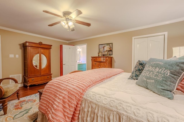 bedroom with ornamental molding, ceiling fan, wood-type flooring, connected bathroom, and a closet