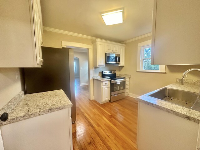 kitchen with crown molding, sink, light hardwood / wood-style floors, white cabinetry, and stainless steel appliances