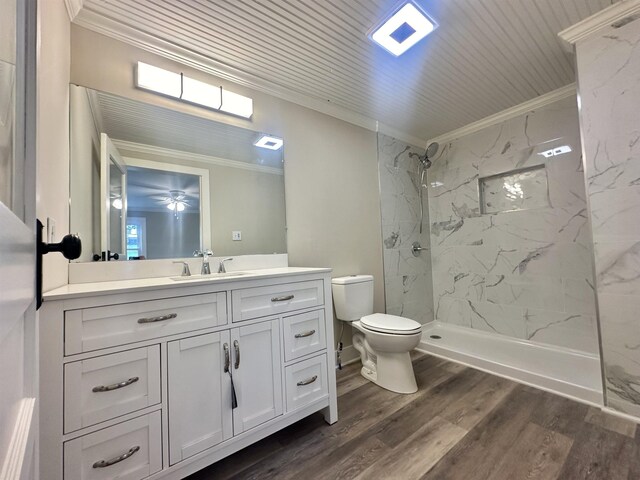 bathroom with a tile shower, vanity, hardwood / wood-style flooring, and ornamental molding