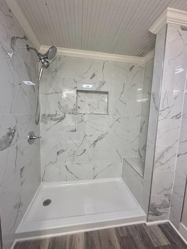 bathroom featuring a tile shower, wood-type flooring, and crown molding