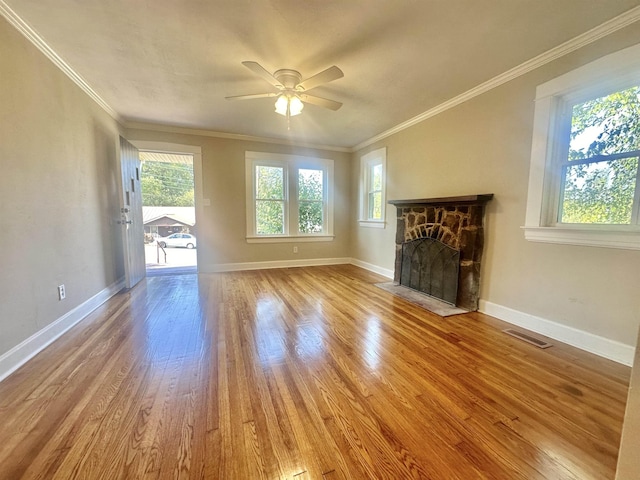 unfurnished living room featuring ceiling fan, a fireplace, light hardwood / wood-style floors, and ornamental molding