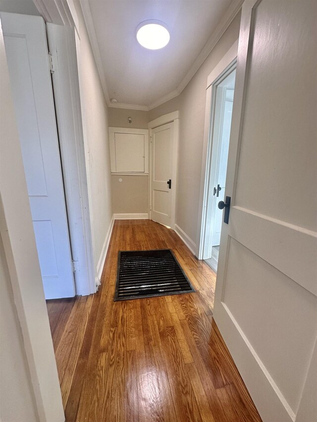 corridor with ornamental molding and hardwood / wood-style flooring