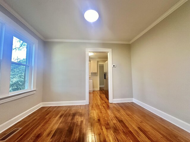 unfurnished room featuring hardwood / wood-style floors and crown molding