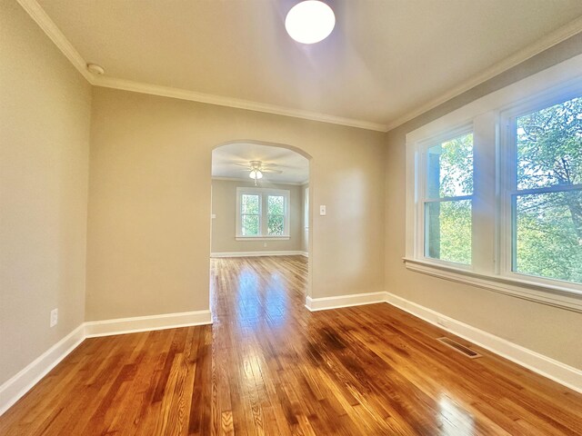 empty room featuring hardwood / wood-style flooring, plenty of natural light, and ornamental molding