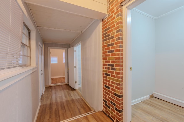 hall featuring crown molding, light wood-style flooring, and baseboards