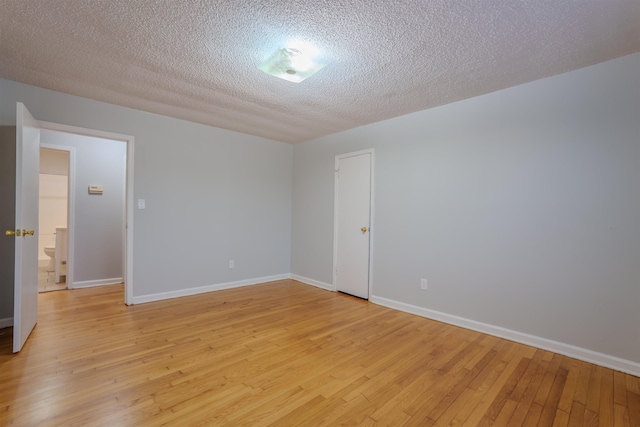 unfurnished room featuring baseboards, a textured ceiling, and light wood finished floors