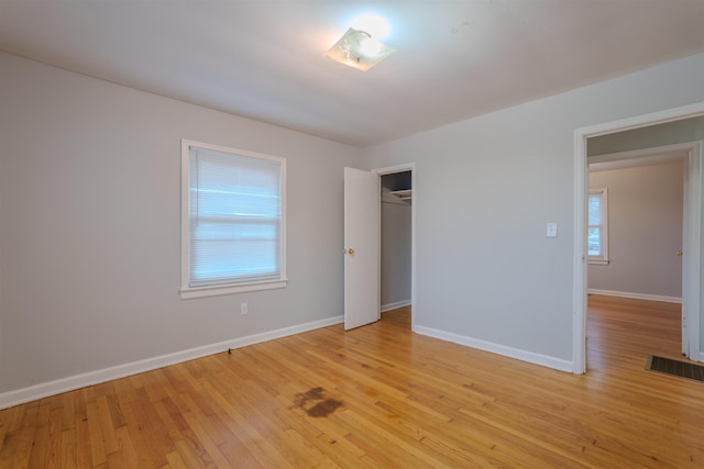 unfurnished bedroom with baseboards, multiple windows, and light wood-style floors